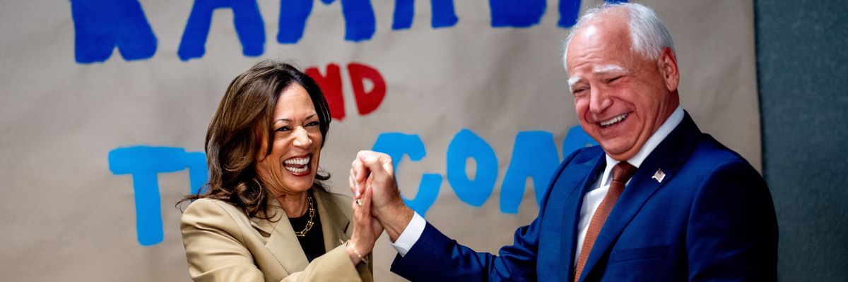 Kamala Harris and Tim Walz laugh and hold hands.