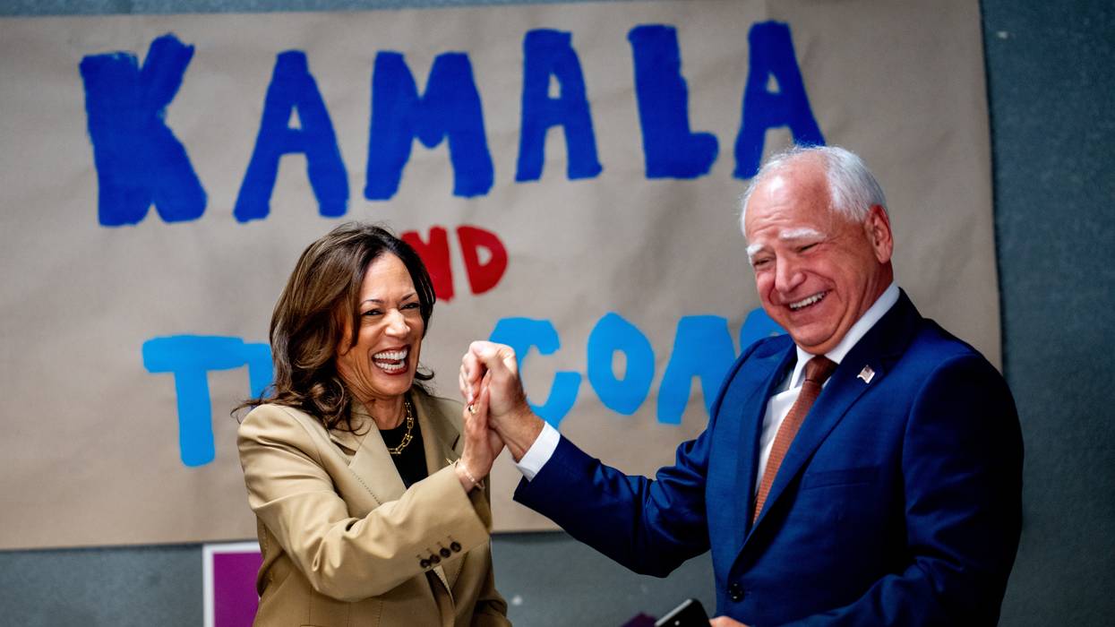 Kamala Harris and Tim Walz laugh and hold hands.