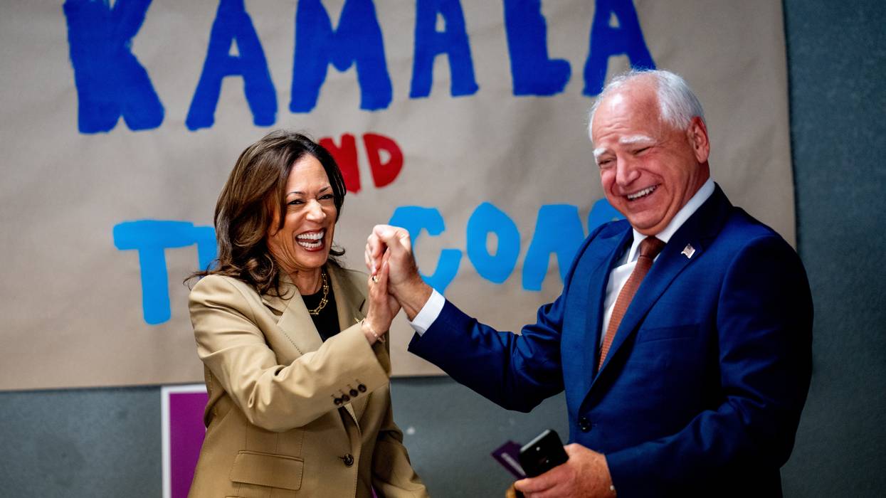 Kamala Harris and Tim Walz laugh and hold hands.