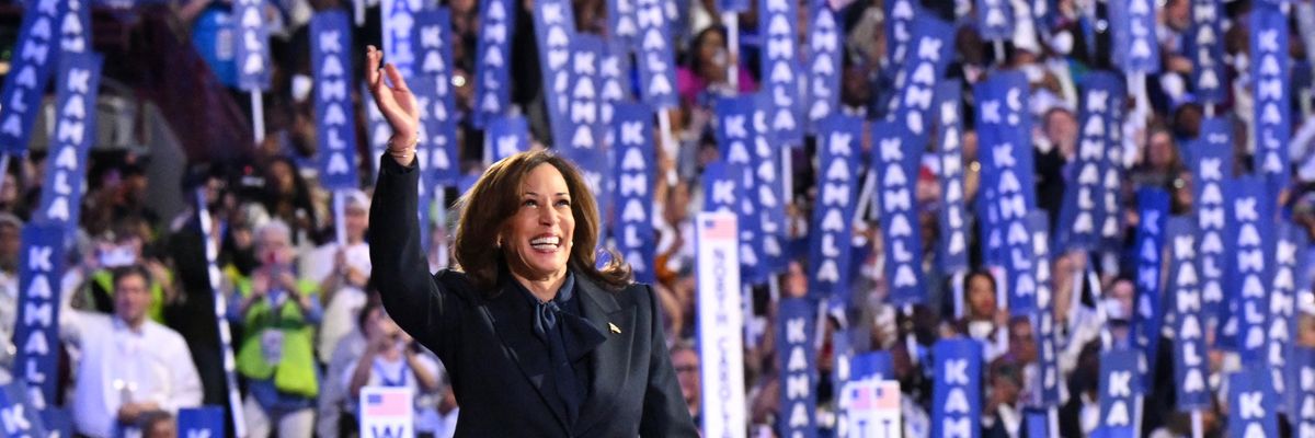 Kamala Harris at the DNC with signs behind her.
