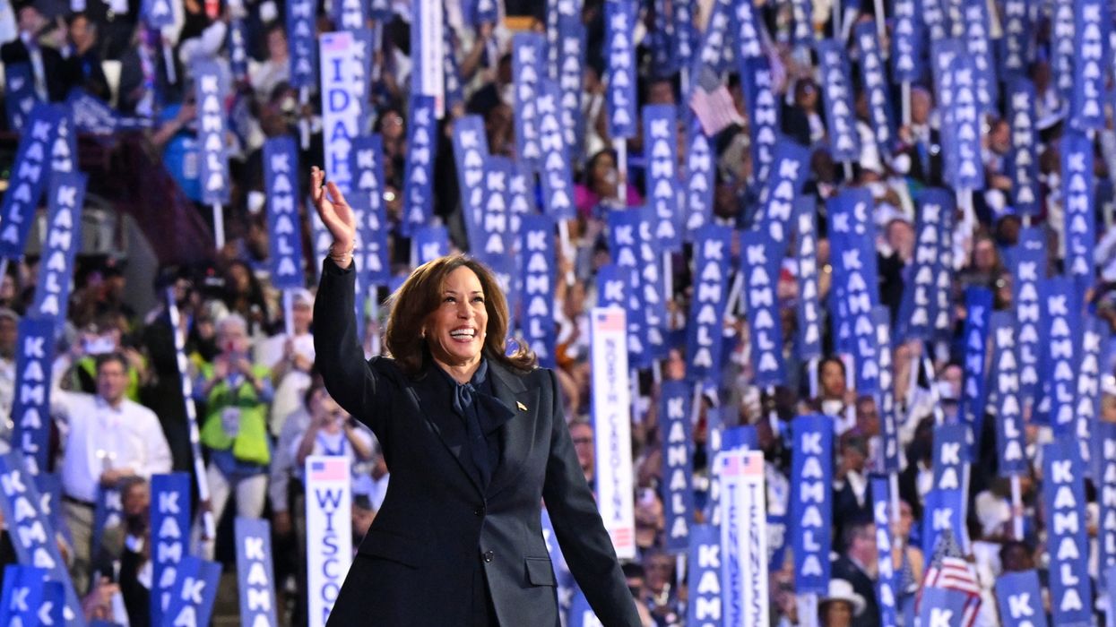 Kamala Harris at the DNC with signs behind her.