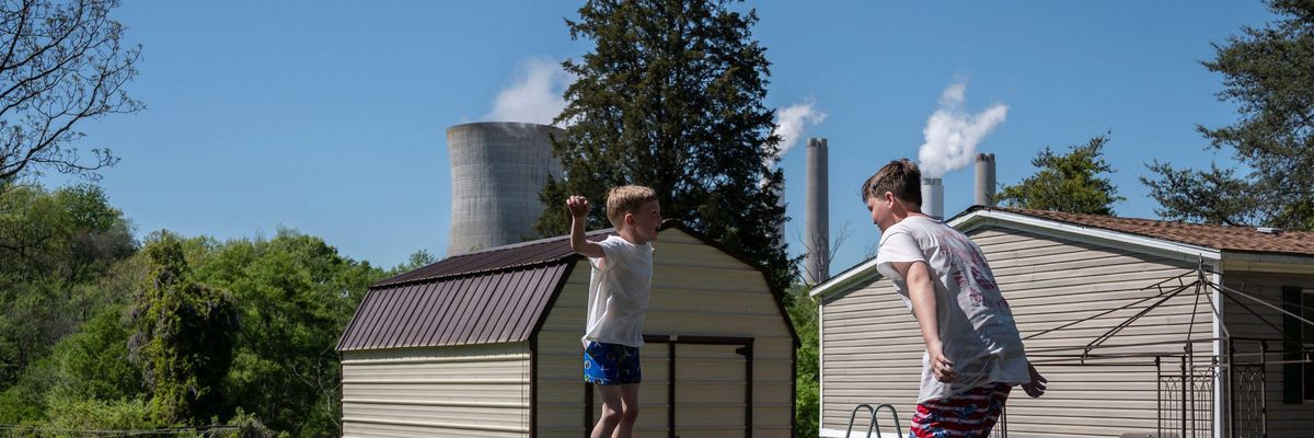 Kids jump on a trampoline at their grandparents' home as steam rises from the Miller coal power plant in Adamsville, Alabama on April 11, 2021.  (Photo: by Andrew Caballero-Reynolds/AFP via Getty Images)