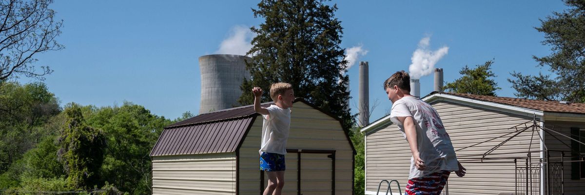 Kids jump on a trampoline at their grandparents' home as steam rises from the Miller coal power plant in Adamsville, Alabama on April 11, 2021.  (Photo: by Andrew Caballero-Reynolds/AFP via Getty Images)