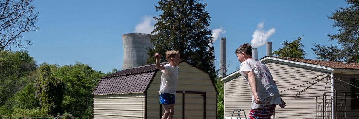 Kids jump on a trampoline at their grandparents' home as steam rises from the Miller coal power plant in Adamsville, Alabama on April 11, 2021. (Photo: by Andrew Caballero-Reynolds/AFP via Getty Images)