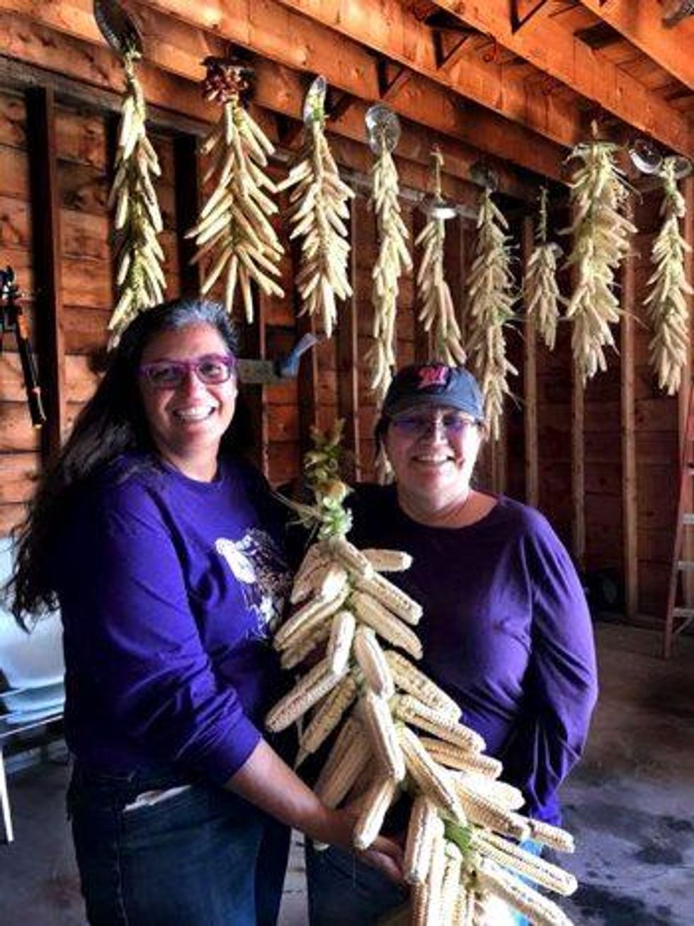 Laura Manthe and Michelle Webster, members of the Ohe*laku farming cooperative, which grows indigenous white corn on the Oneida Nation's Wisconsin reservation, display a corn braid. (Photo: Lea Zeise)