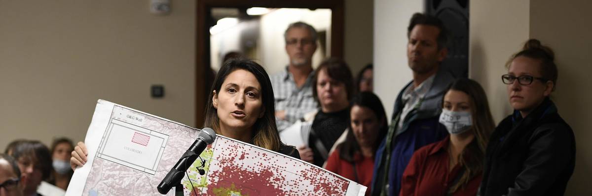 Lauren Petrie, of Food & Water Watch, holds up a map showing all of the fracking sites along the Front Range as she addresses members of the Colorado Oil and Gas Conservation Commission during a public comment session on October 30, 2017 in Denver.