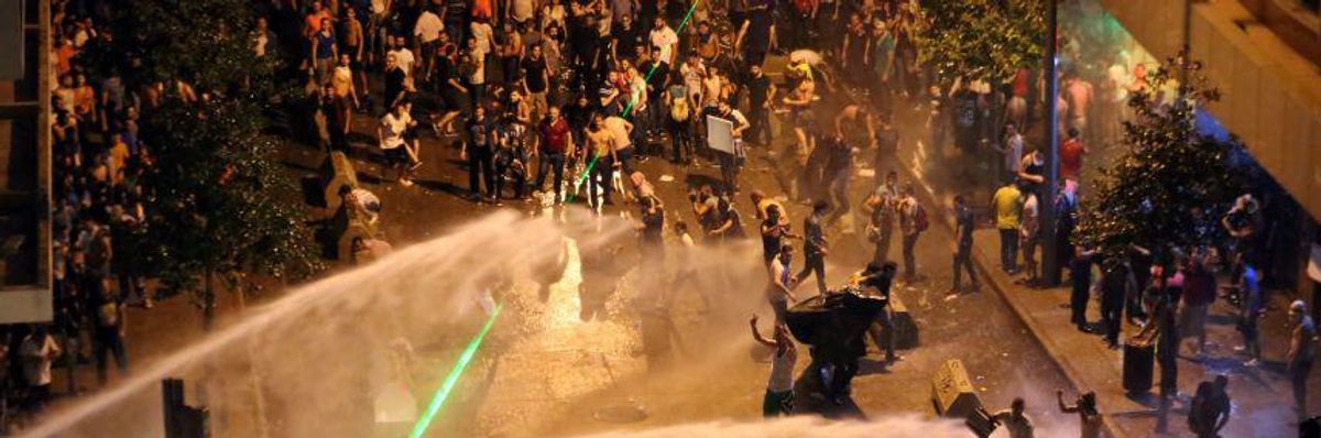 Lebanese activists shout 'Revolution! Revolution!' as they are sprayed by riot police using water cannons Sunday evening in Beirut, Lebanon