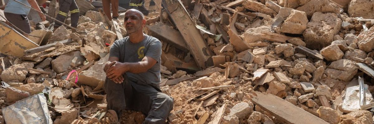 Lebanese are seen among the rubble of an Israeli airstrike in Beirut