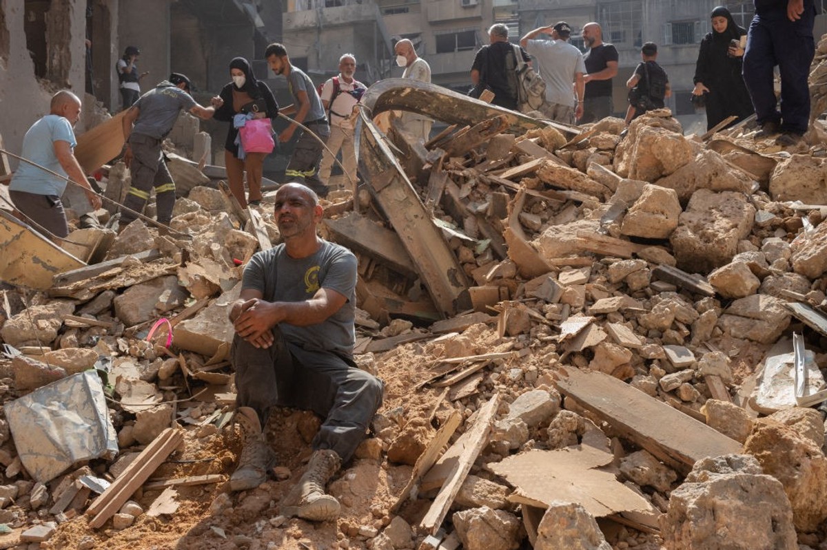Lebanese are seen among the rubble of an Israeli airstrike in Beirut