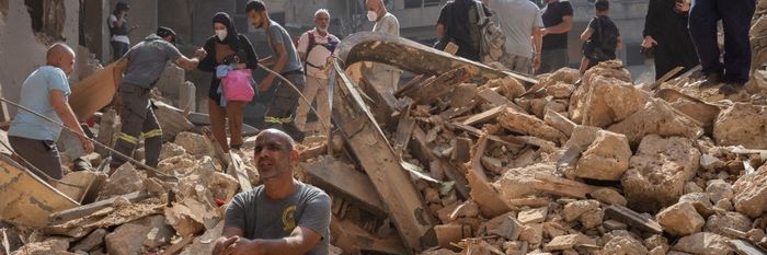 Lebanese are seen among the rubble of an Israeli airstrike in Beirut