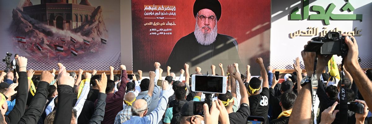 Lebanese watch Hassan Nasrallah's speech on a massive video screen while raising their fists.