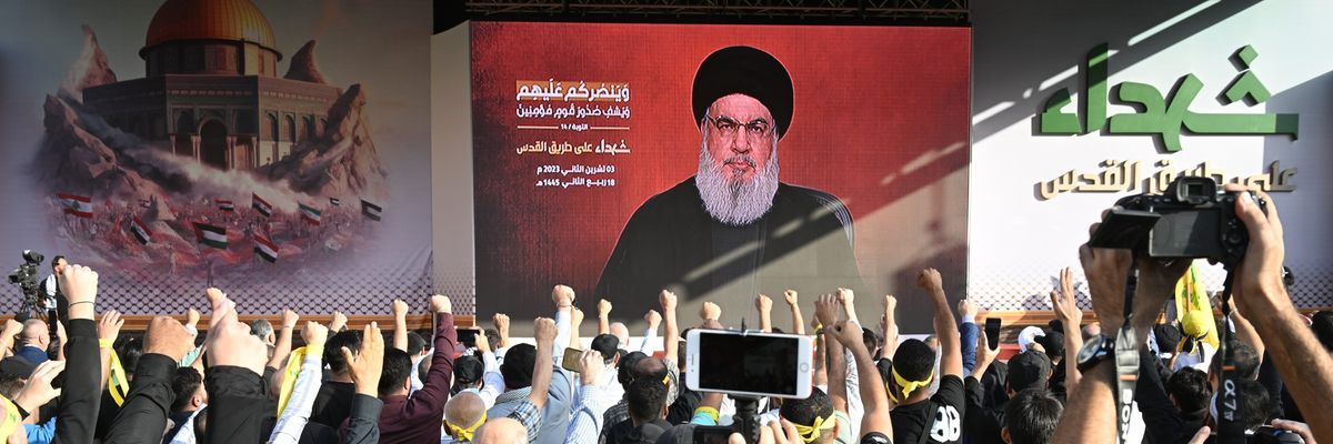 Lebanese watch Hassan Nasrallah's speech on a massive video screen while raising their fists.