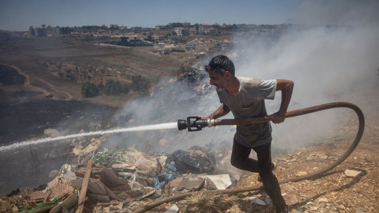 Lebanon civilian putting out fire from Israeli bombs.