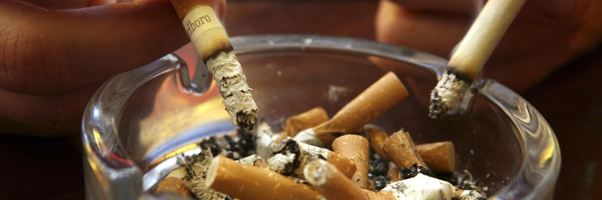Lit cigarettes are held above a filled ashtray. (Photo: Matt Cardy/Getty Images)