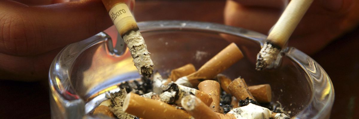 Lit cigarettes are held above a filled ashtray.  (Photo: Matt Cardy/Getty Images)