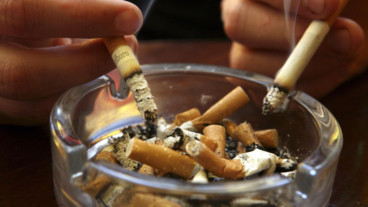 Lit cigarettes are held above a filled ashtray.  (Photo: Matt Cardy/Getty Images)