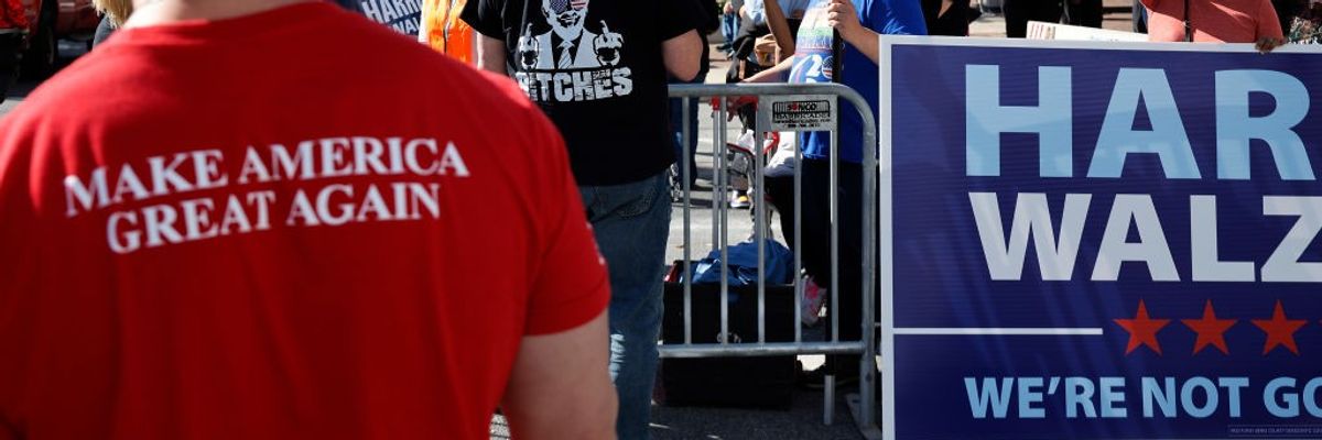 MAGA supporter standing near Harris-Walz sign