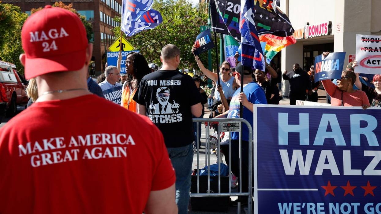 MAGA supporter standing near Harris-Walz sign