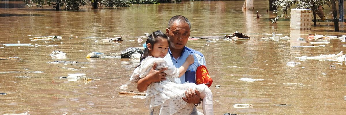 Man carries child through flooded waters