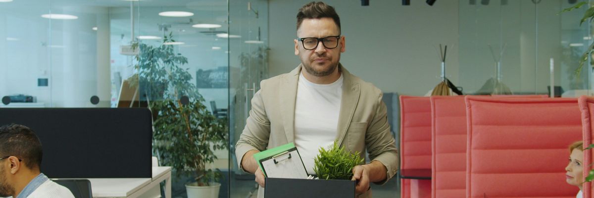 Man holding box of belongings after being fired.