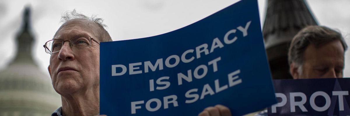 Man holding sign that says "Democracy Is Not for Sale"