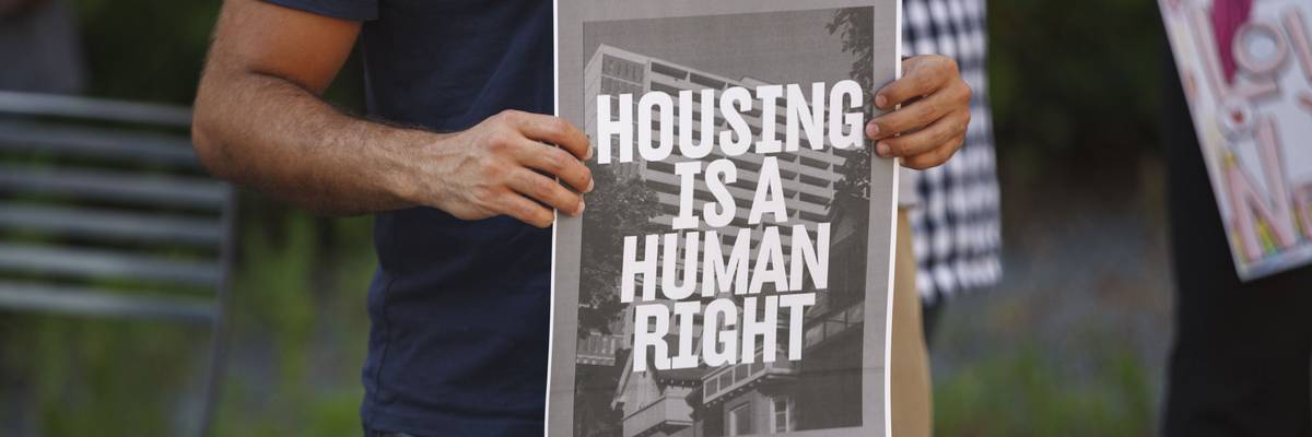Man holds a placard that says Housing is a human right
