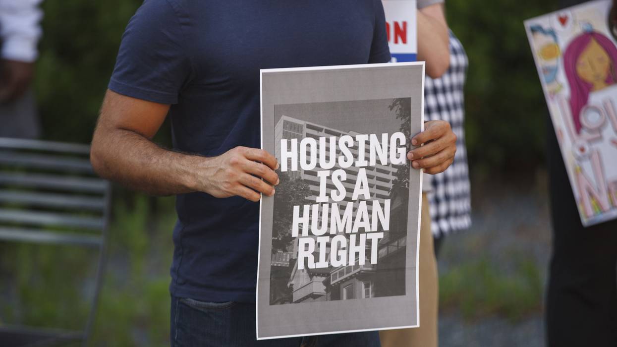 Man holds a placard that says Housing is a human right