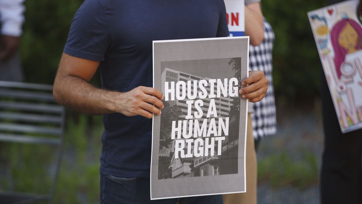 Man holds a placard that says Housing is a human right