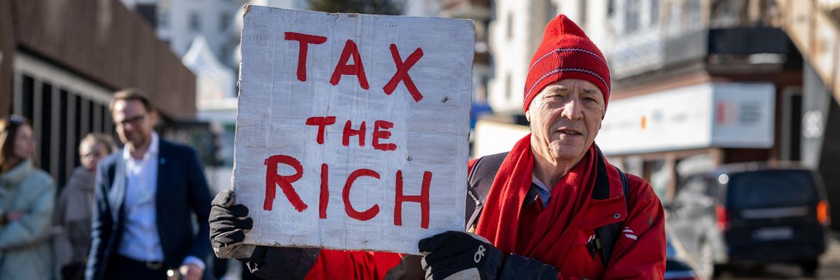Man holds "Tax the rich" sign