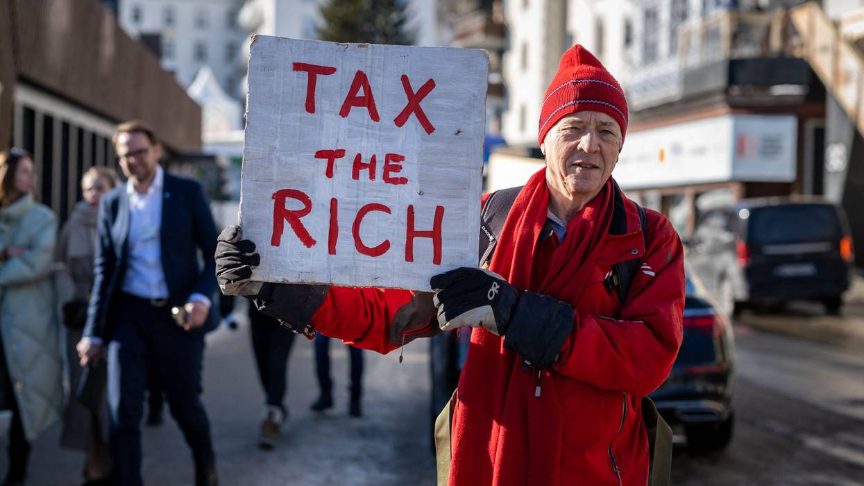 Man holds "Tax the rich" sign