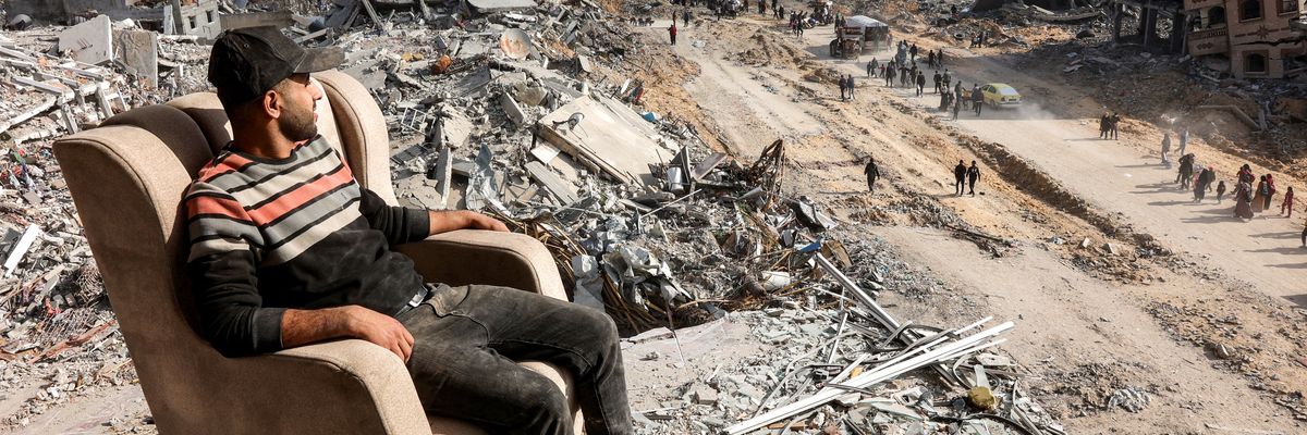 Man in Gaza sits in chair in front of rubble.