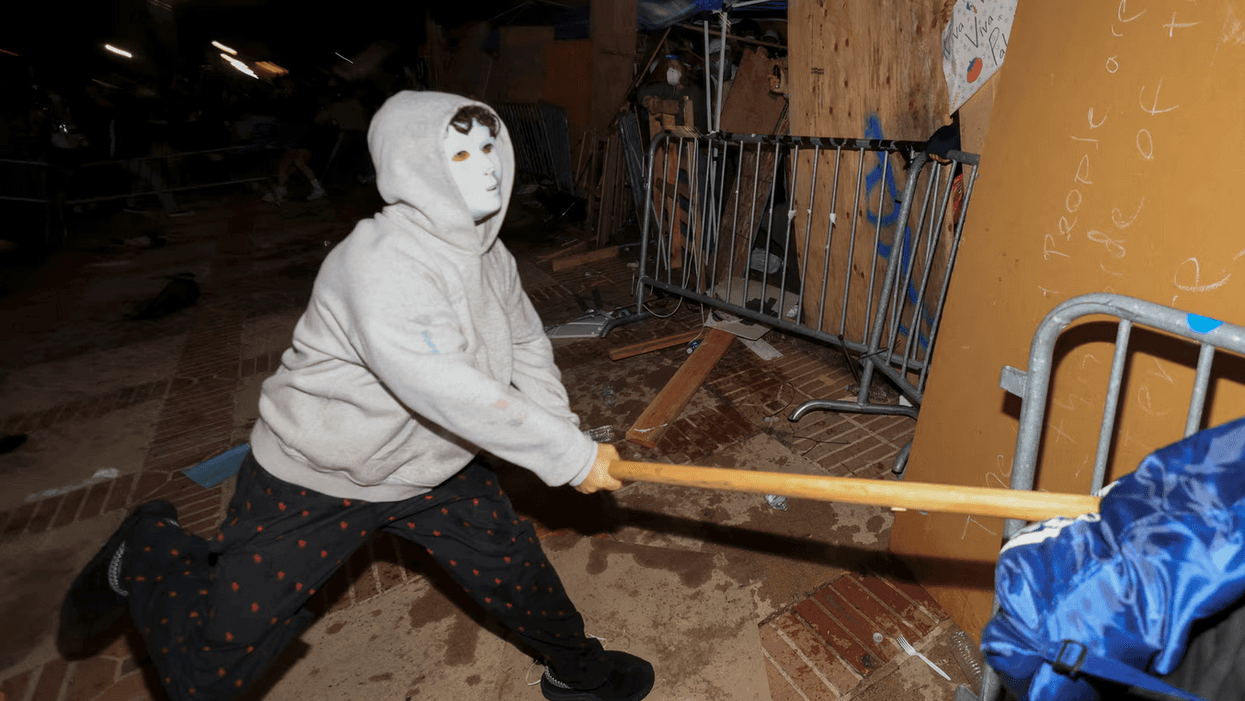 man in mask wielding wooden stick
