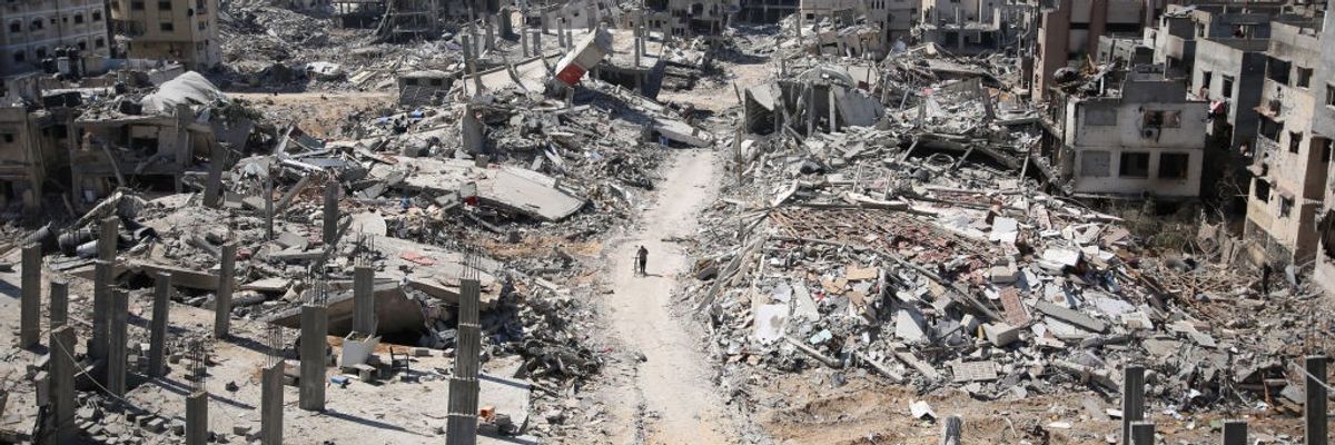 man pushing bicycle in the distance, amid rubble