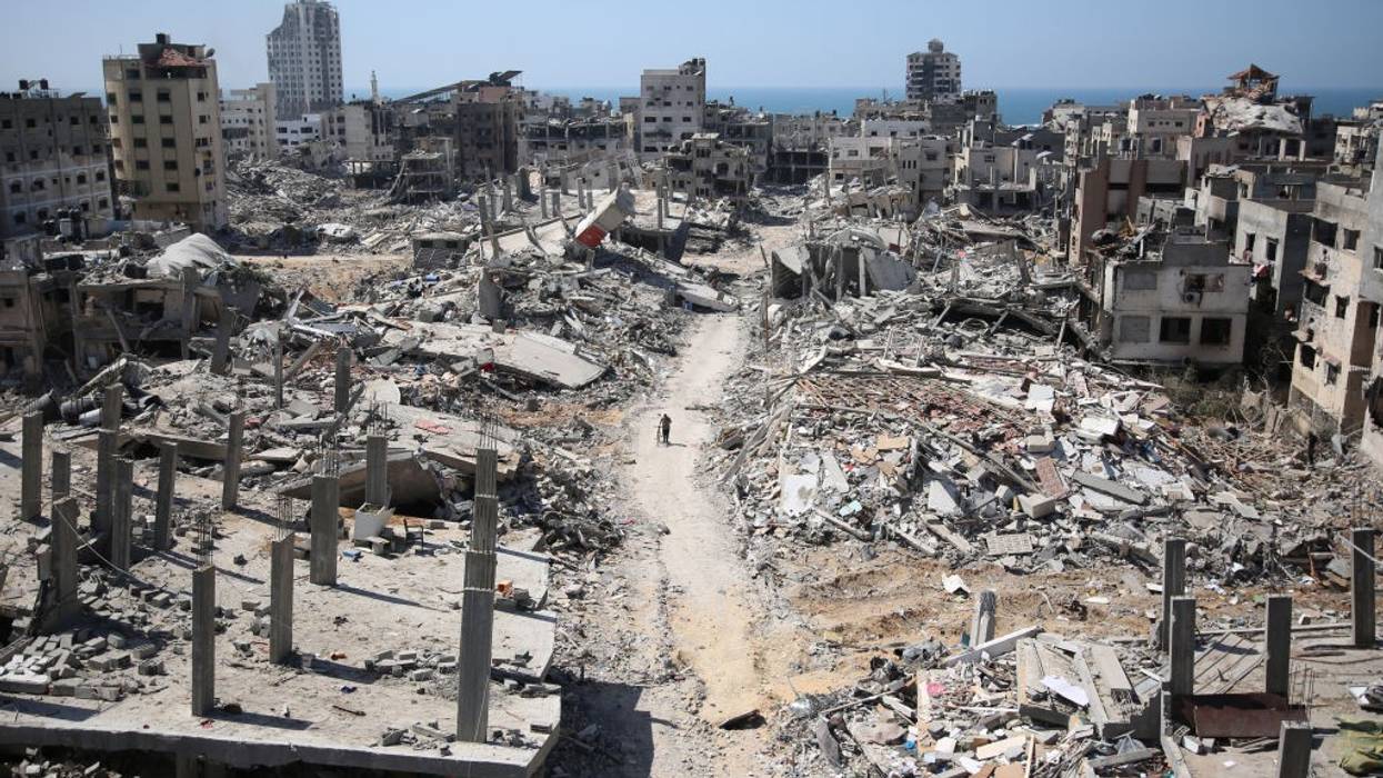 man pushing bicycle in the distance, amid rubble