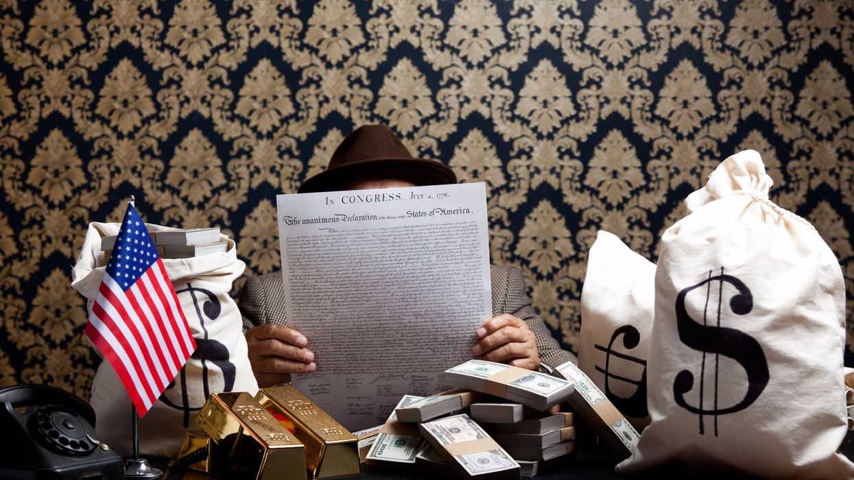 Man reading US Constitution surrounded by money.