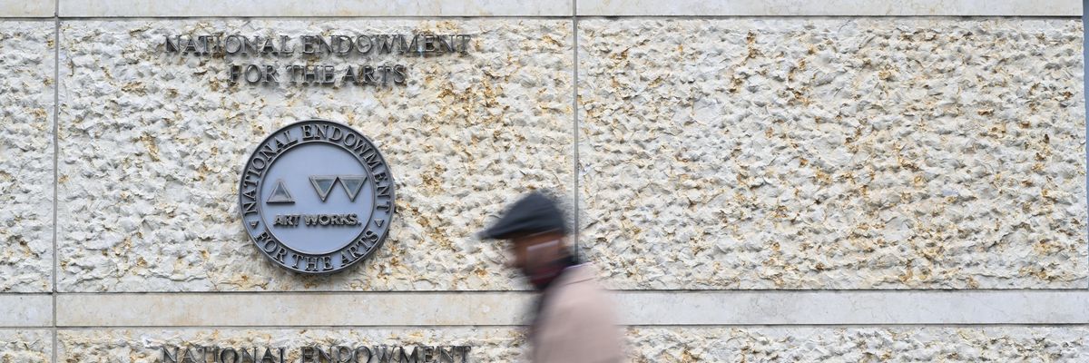 man walks past the building that houses the National Endowment for the Arts and the National Endowment for the Humanities