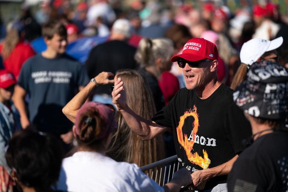 Man wearing a QAnon t-shirt waits in line for a Trump rally