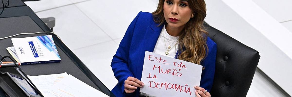 Marcela Villatoro, an opposition lawmaker in El Salvador, holds a sign that reads "Democracy Died Today"