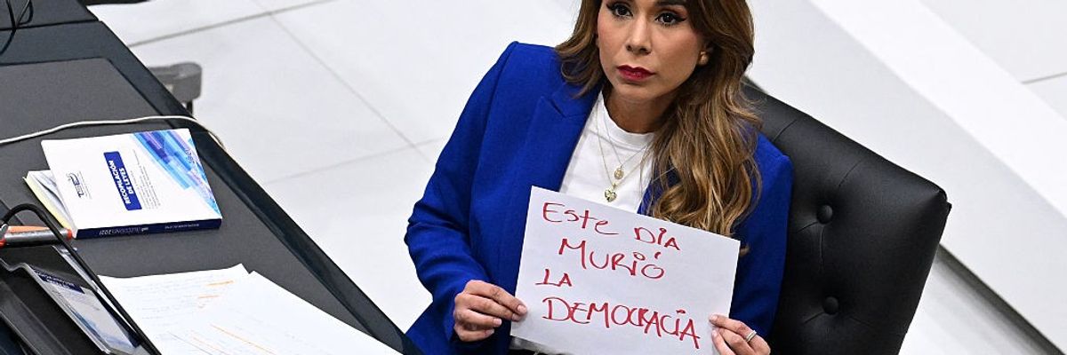 Marcela Villatoro, an opposition lawmaker in El Salvador, holds a sign that reads "Democracy Died Today"