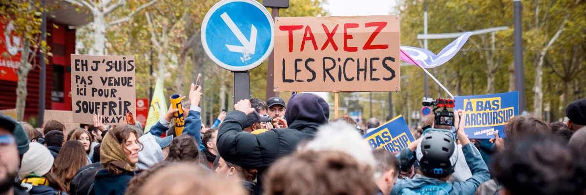 March in Paris with sign saying Tax the rich in French.
