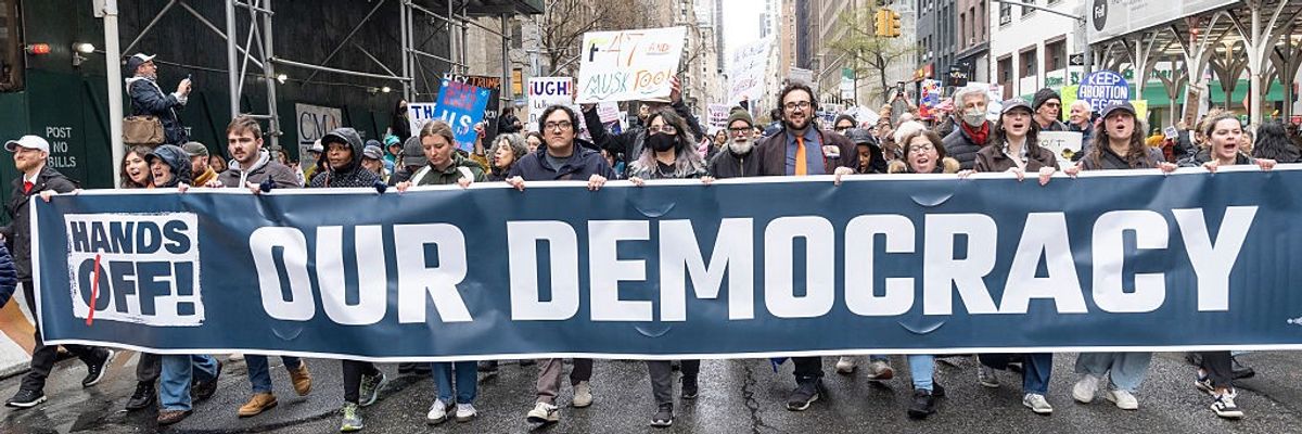 Marchers carry sign reading, "Hands off our democracy."
