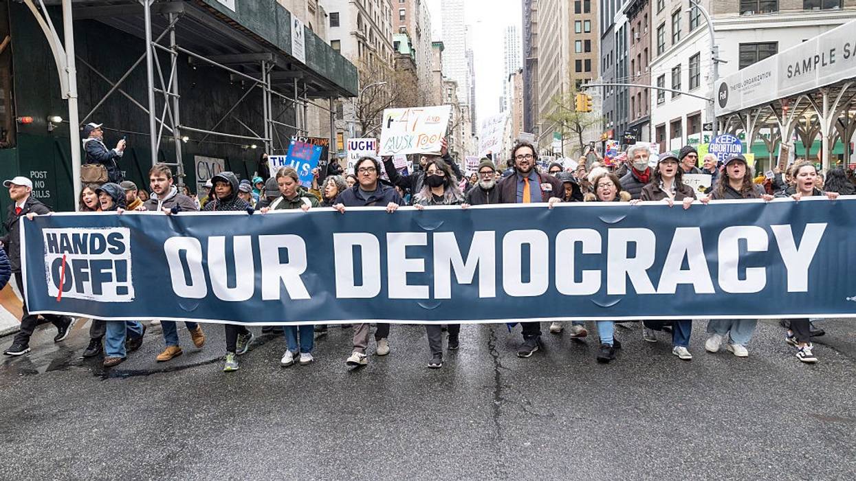 Marchers carry sign reading, "Hands off our democracy."