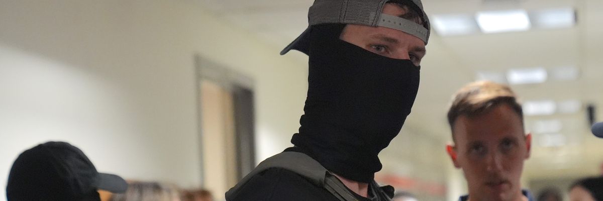 Masked federal agents wait outside the immigration court at the Jacob K. Javits building