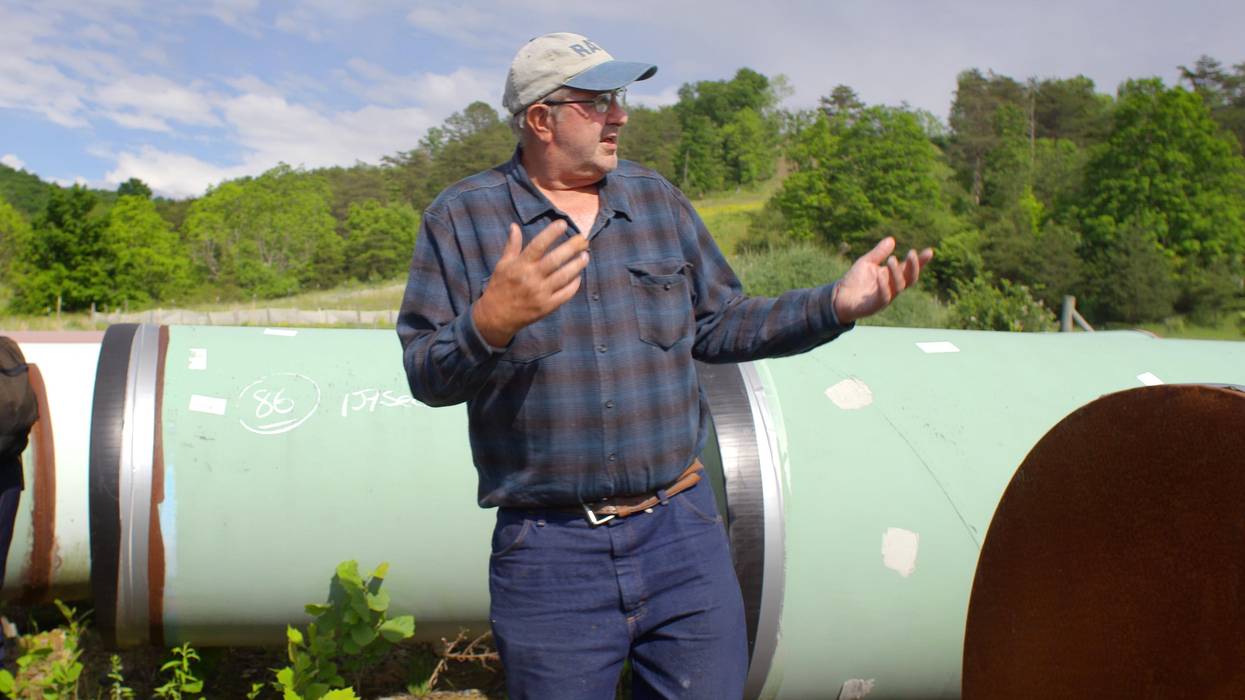 Maury Johnson standing near his West Virginia farm with pieces of pipeline in the background.