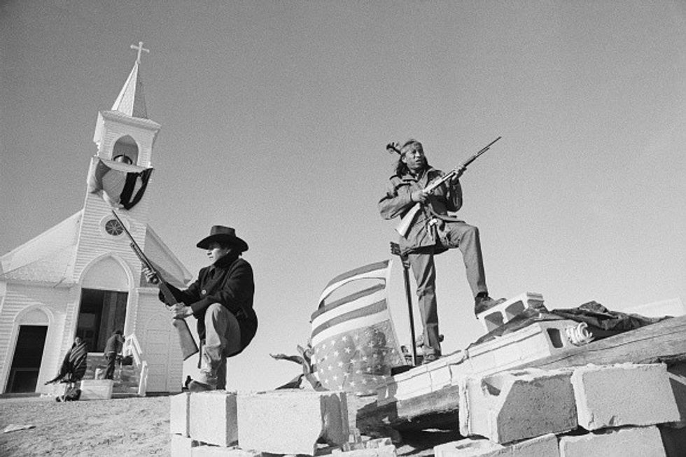 Members of AIM and local Oglala Sioux stand armed guard outside a church during Standing Rock occupation. 