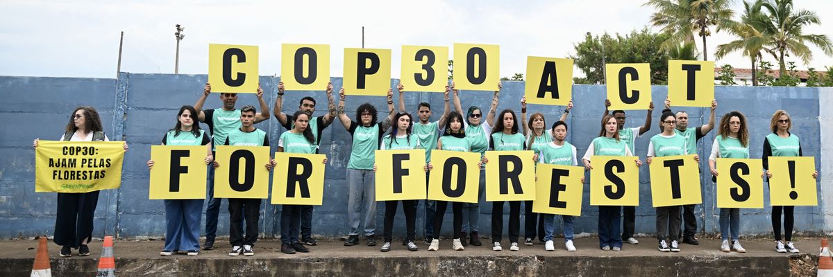 Members of Greenpeace hold sign demanding action to save the forests
