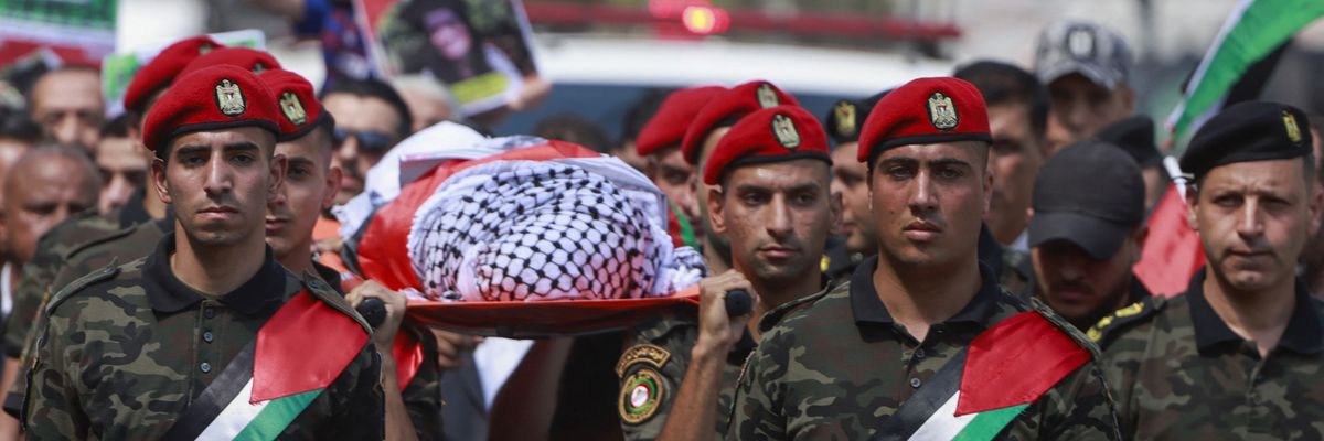 Members of Palestinian security forces carry the body of Aysenur Eygi