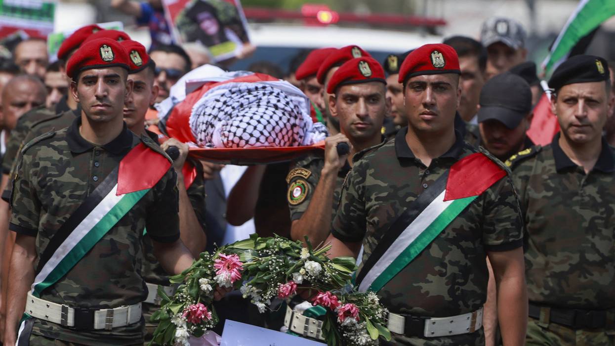 Members of Palestinian security forces carry the body of Aysenur Eygi