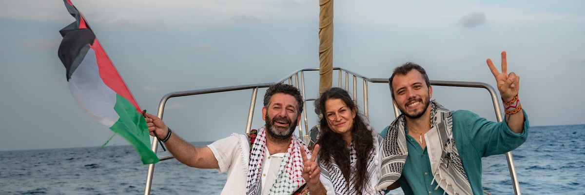 Members of the Global Sumud Flotilla wave a Palestinian flag and make a peace symbol with their hands.