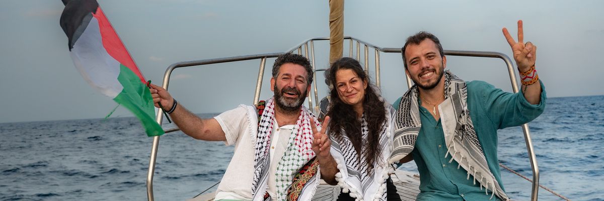 Members of the Global Sumud Flotilla wave a Palestinian flag and make a peace symbol with their hands.